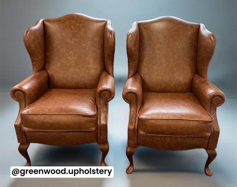 A pair of Queen Anne-style wing chairs in antiqued tan leather.
