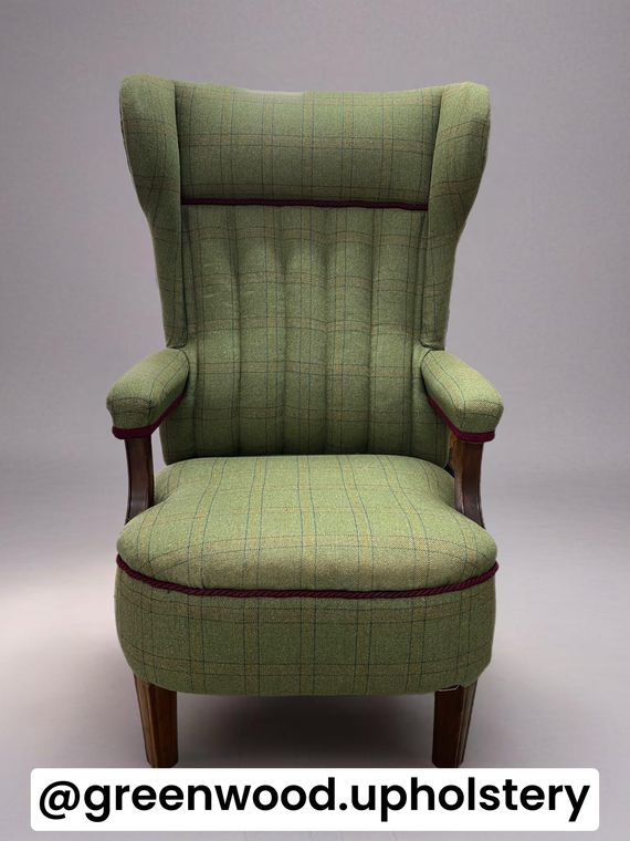 Wing chair in green check tweed with burgundy cord piping.