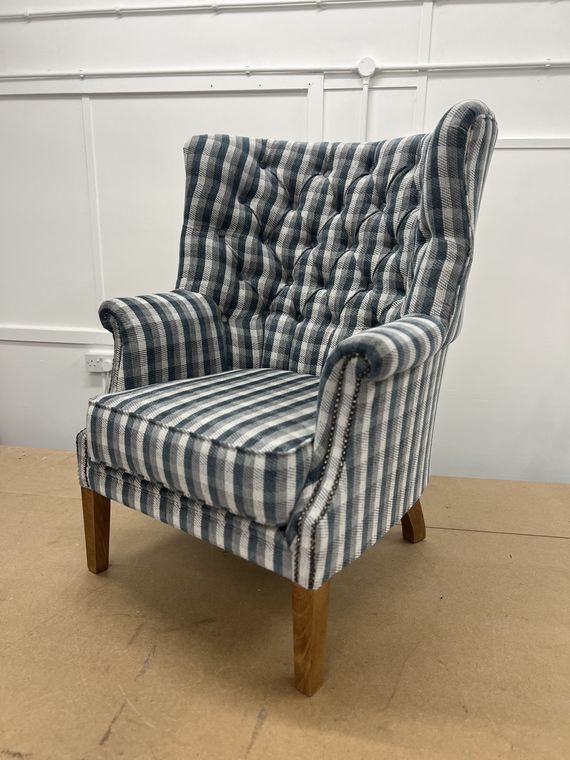 Deep-buttoned wing chair in a blue tartan check.