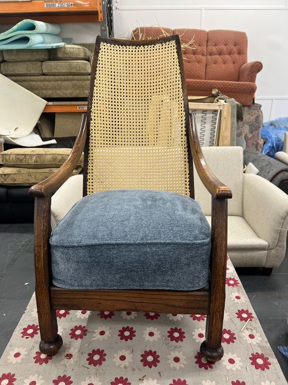 Caned-back armchair with a blue wool cushion.