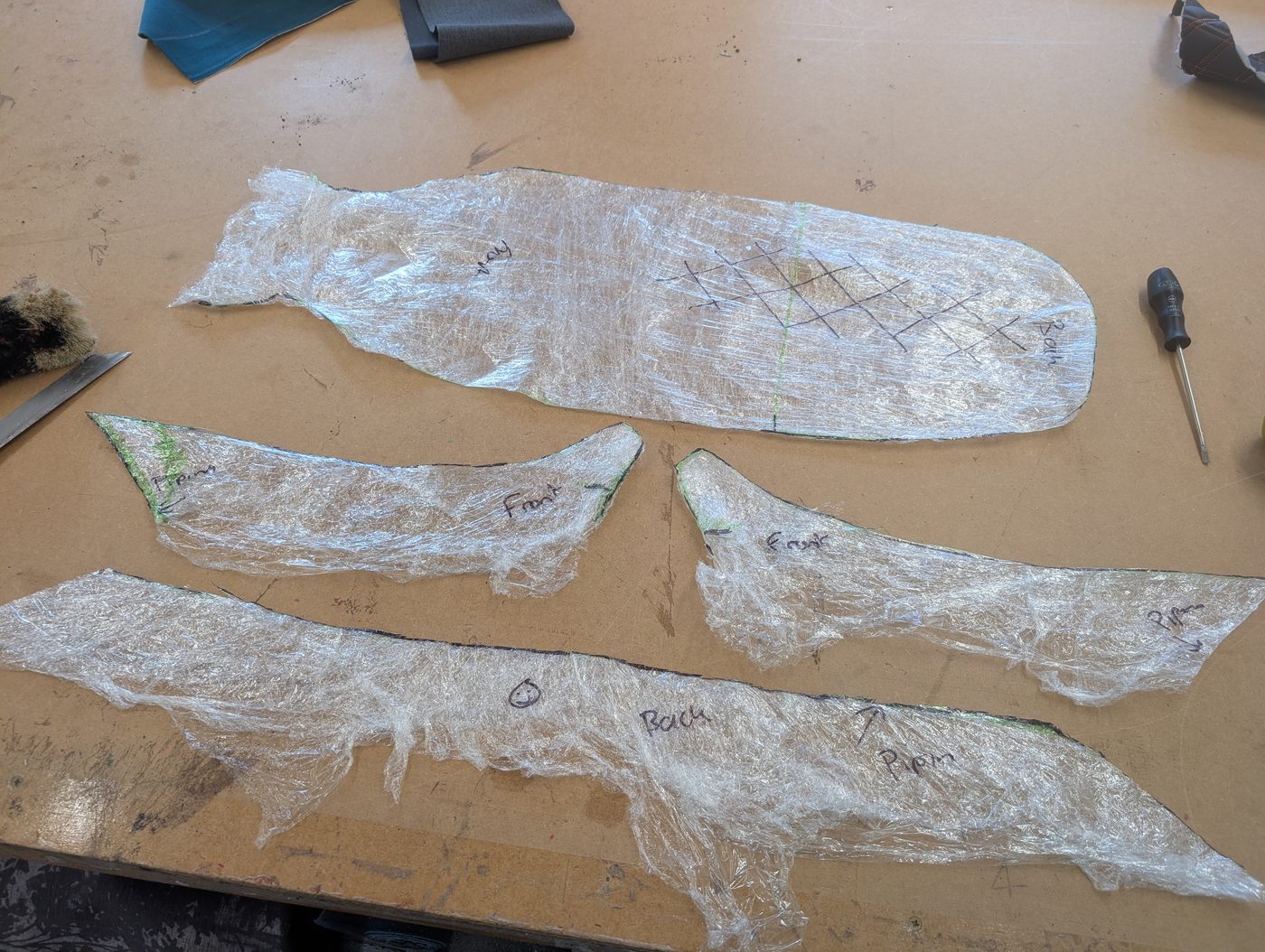 The shrink-wrap skin cut apart along the marked lines into flat pattern pieces — top, fronts and back, with the piping runs labelled.