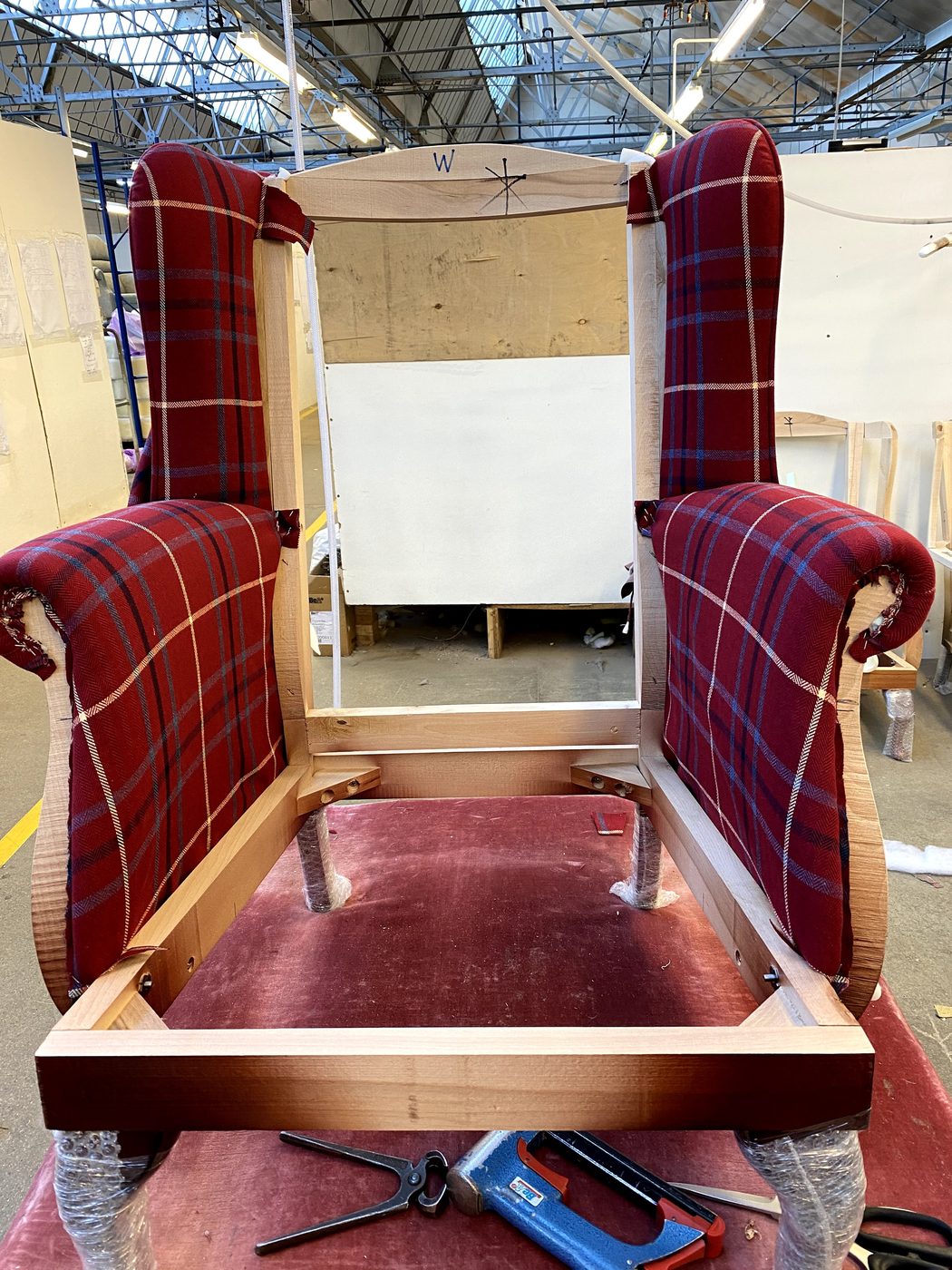 The arms upholstered next, the check running true through the scrolls and lining through with the wings.