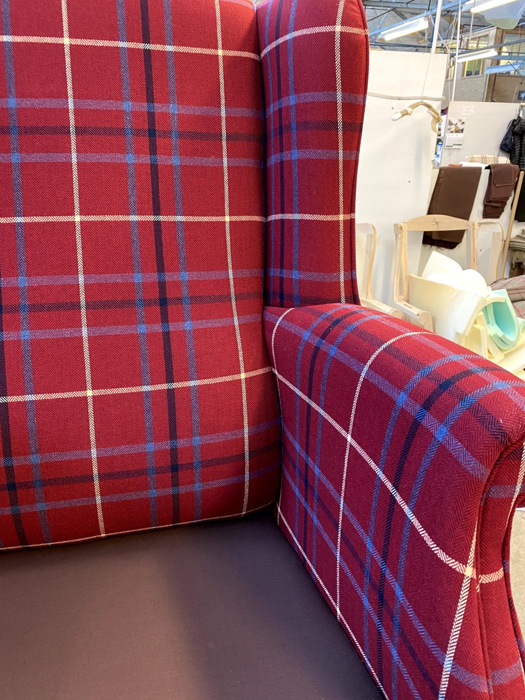 The finished chair — a new-build modern wing chair in red tartan check, every line matched in every direction.